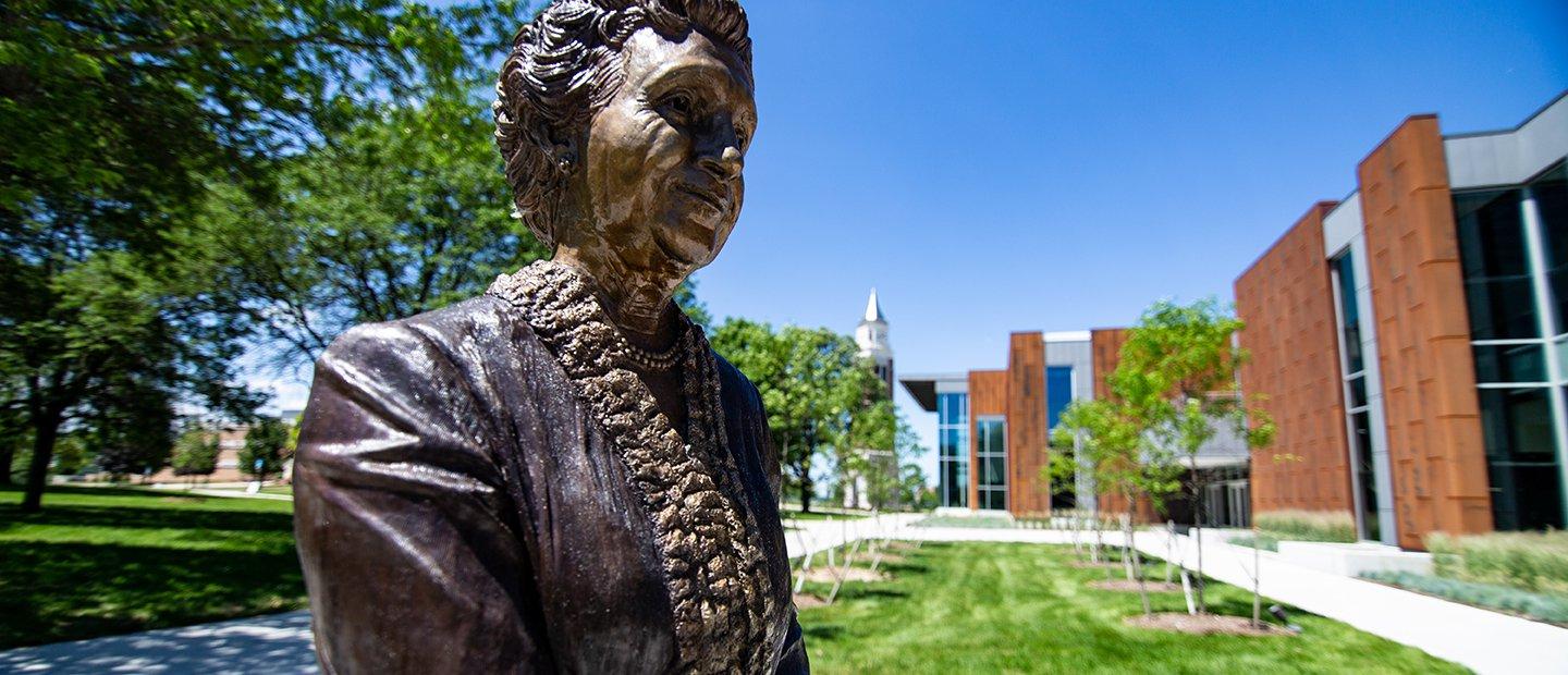 A bronze statue of a woman outside of a building on 365英国上市官网's campus.