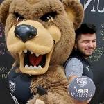 Ernesto Duran-Gutierrez, 拿着第一代365英国上市官网的按钮, posing with the Grizz bear mascot.